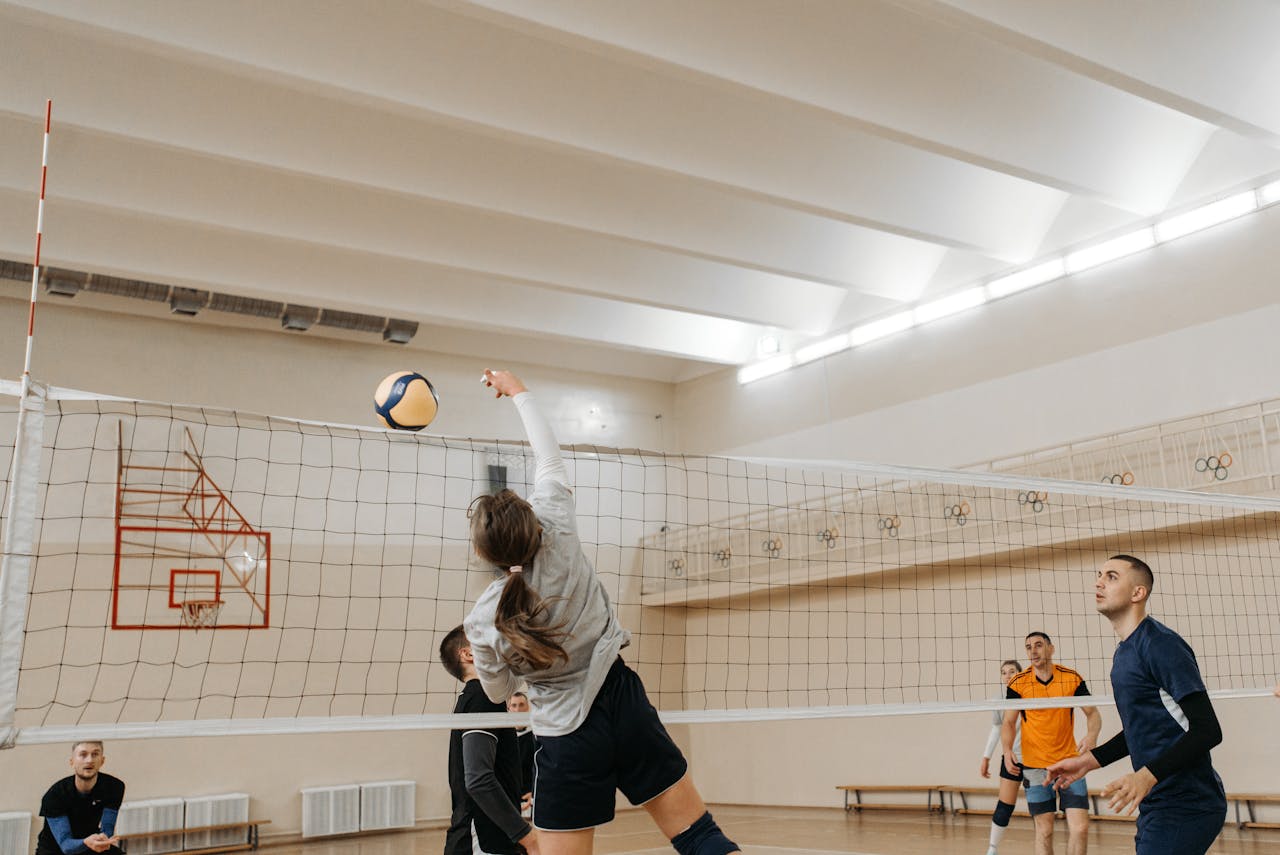 Players engaging in a competitive indoor volleyball match with dynamic action and teamwork.